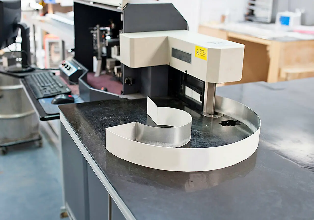 Precision letter bending machine shaping a metal letter for custom 3D signage fabrication.